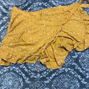 A yellow skirt with white flowers and green leafs